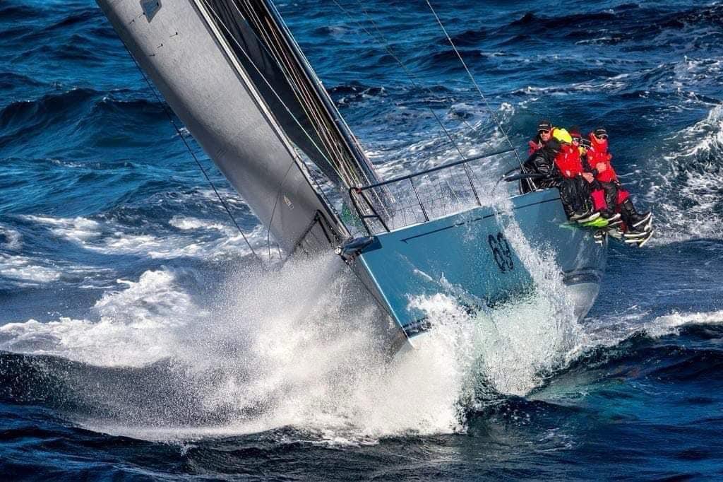 Offshore yacht cutting through a steep wave